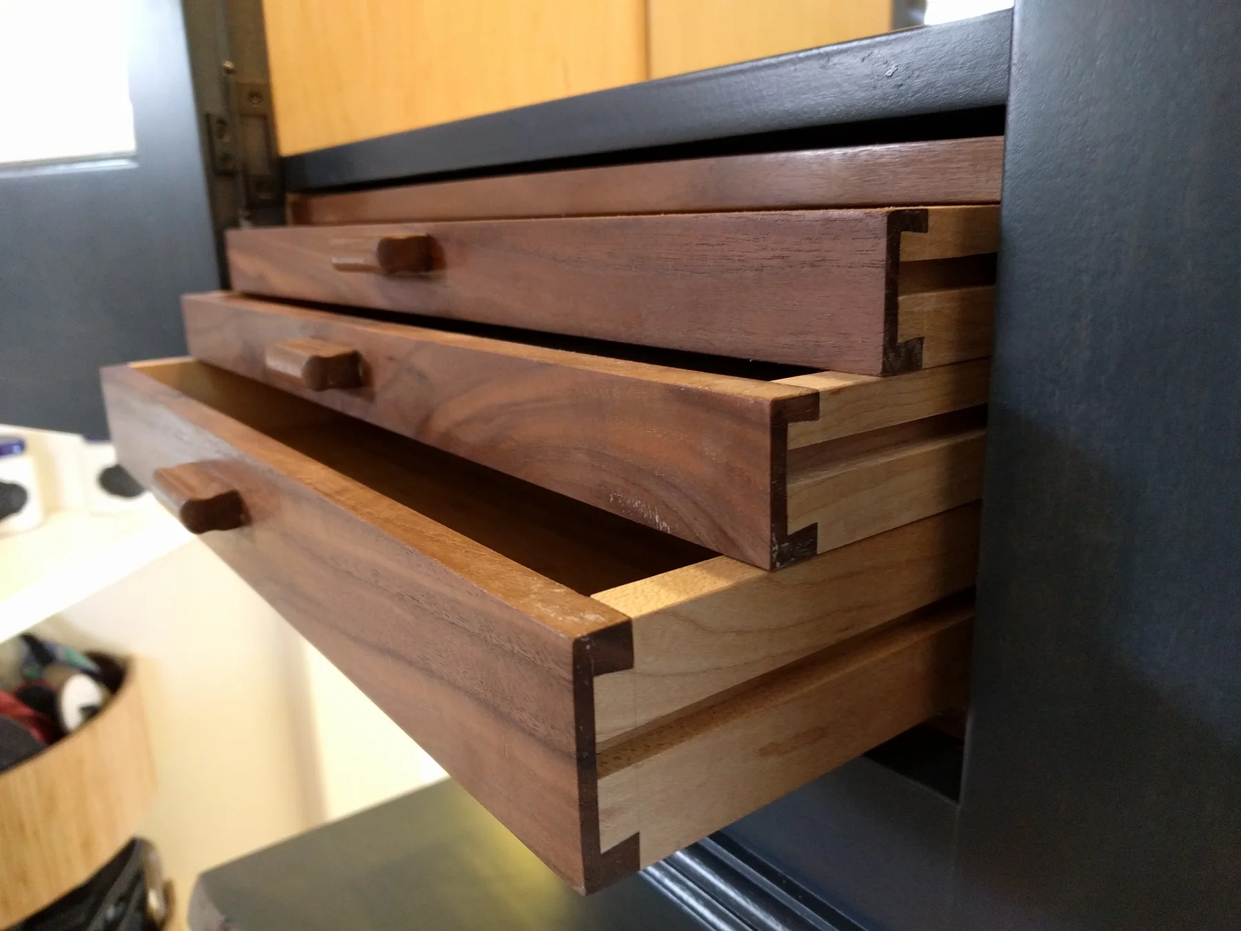Solid wood dovetailed drawers extended from a dark cabinet